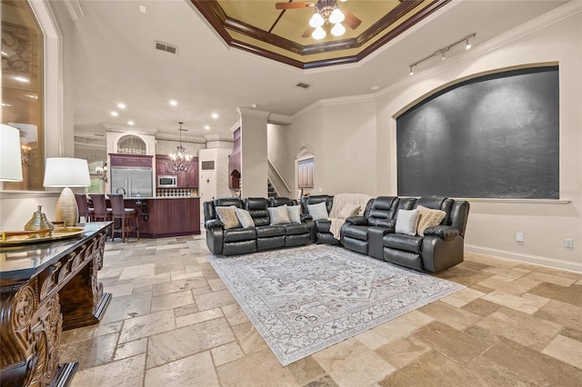 cinema room with crown molding, ceiling fan with notable chandelier, and a tray ceiling