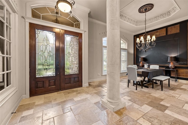 entryway featuring a raised ceiling, crown molding, french doors, an inviting chandelier, and decorative columns