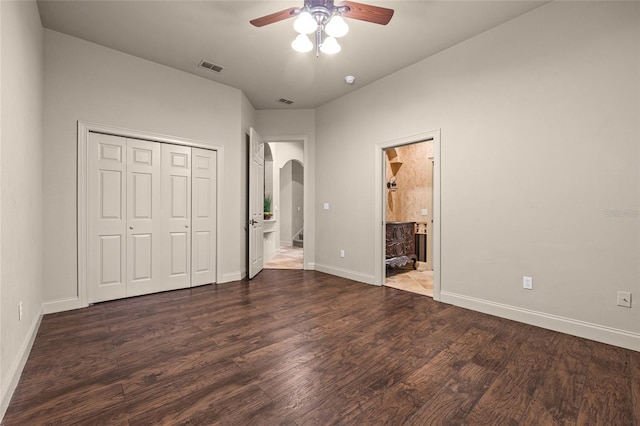 unfurnished bedroom with ceiling fan, connected bathroom, a closet, and dark hardwood / wood-style floors