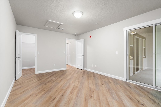 spare room with a textured ceiling and light hardwood / wood-style floors