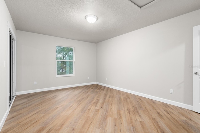 empty room featuring a textured ceiling and light hardwood / wood-style flooring