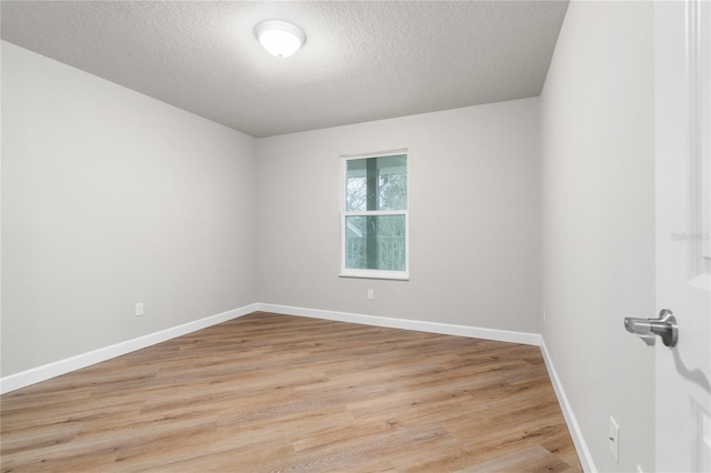 spare room with a textured ceiling and light wood-type flooring