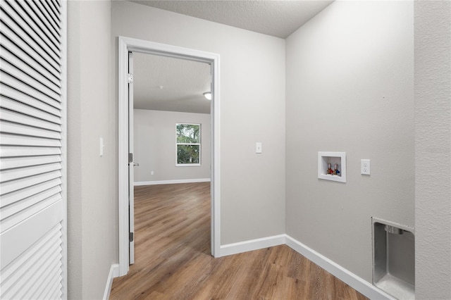 washroom with a textured ceiling, light wood-type flooring, and hookup for a washing machine