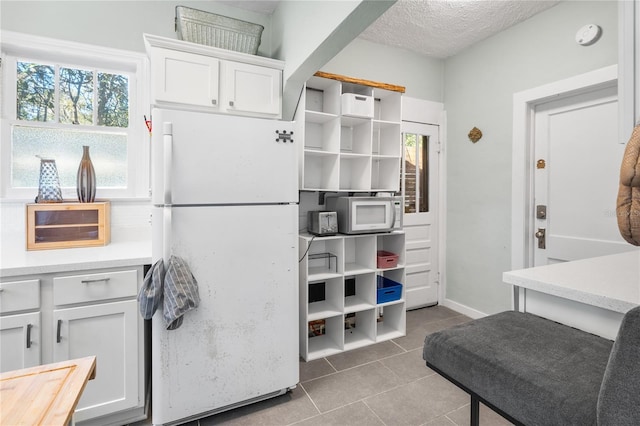 kitchen featuring white cabinetry, white appliances, tile patterned flooring, and a textured ceiling