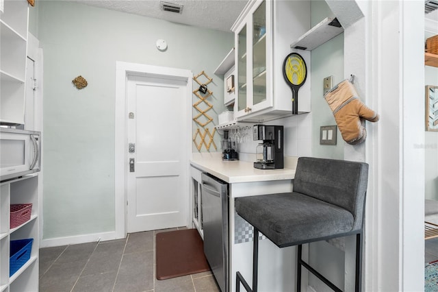 kitchen with tasteful backsplash, dishwasher, dark tile patterned floors, and a textured ceiling