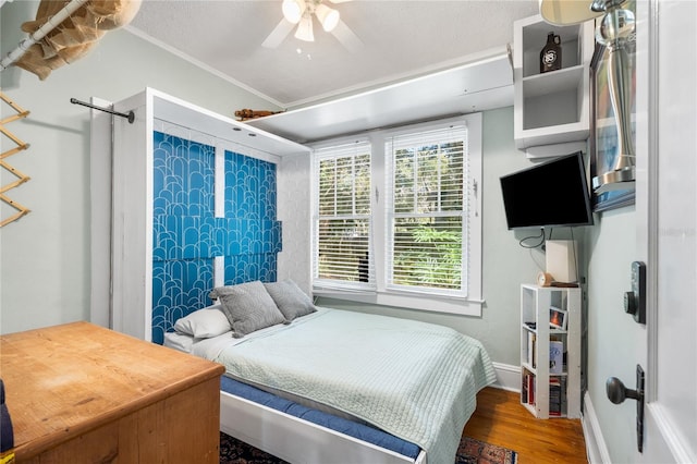 bedroom featuring hardwood / wood-style flooring, ornamental molding, and ceiling fan