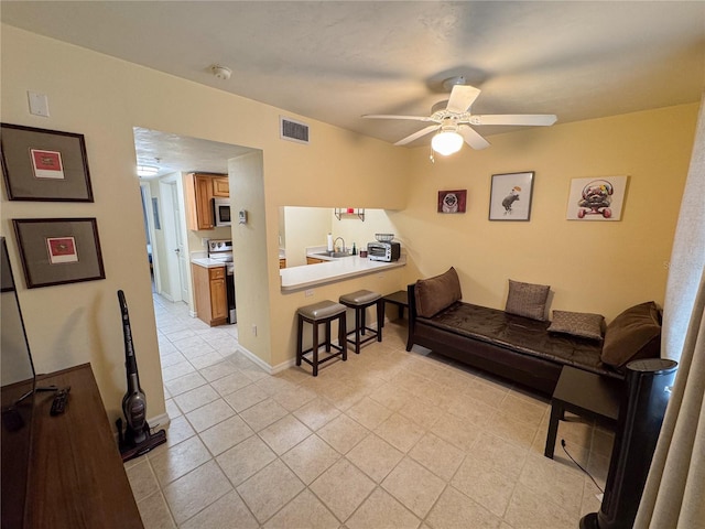 living room with ceiling fan, sink, and light tile patterned floors