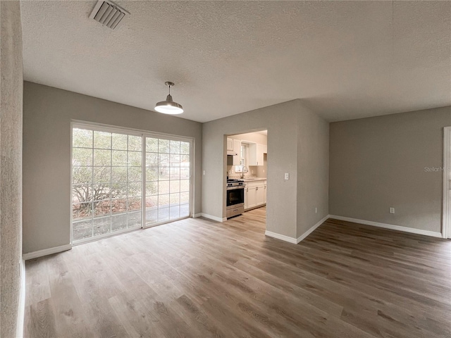 unfurnished living room featuring a textured ceiling and light hardwood / wood-style floors