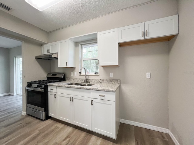 kitchen featuring sink, stainless steel gas stove, white cabinets, and a textured ceiling