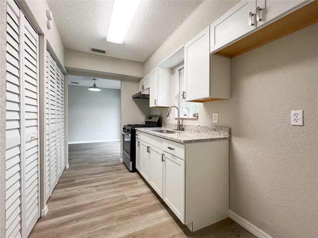 kitchen featuring sink, white cabinetry, stainless steel range with gas cooktop, and a textured ceiling