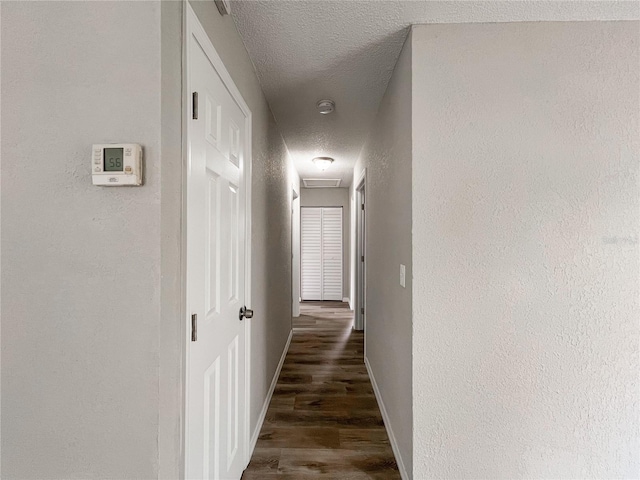 hall featuring a textured ceiling and dark hardwood / wood-style floors