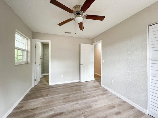 unfurnished bedroom featuring ensuite bath, ceiling fan, and light hardwood / wood-style floors