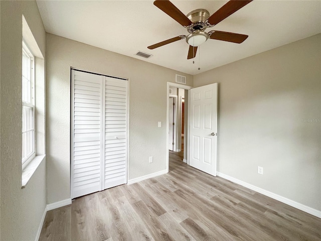 unfurnished bedroom with light wood-type flooring, ceiling fan, and a closet