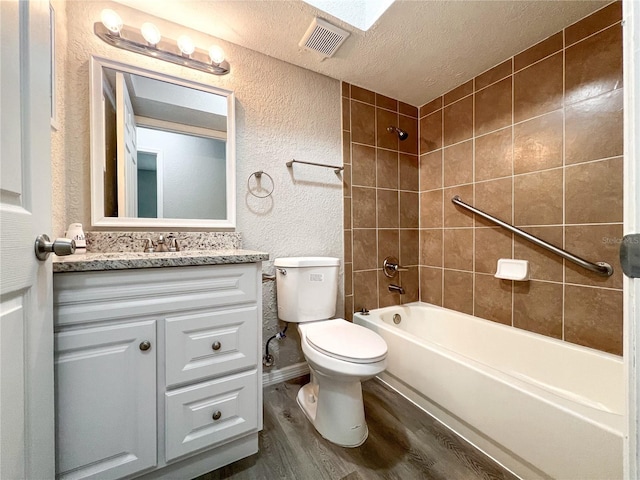 full bathroom with a textured ceiling, toilet, wood-type flooring, vanity, and tiled shower / bath combo