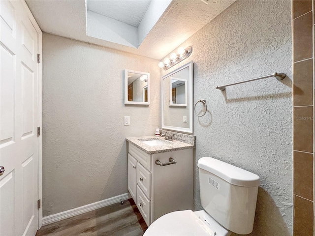 bathroom with toilet, vanity, a textured ceiling, and hardwood / wood-style flooring