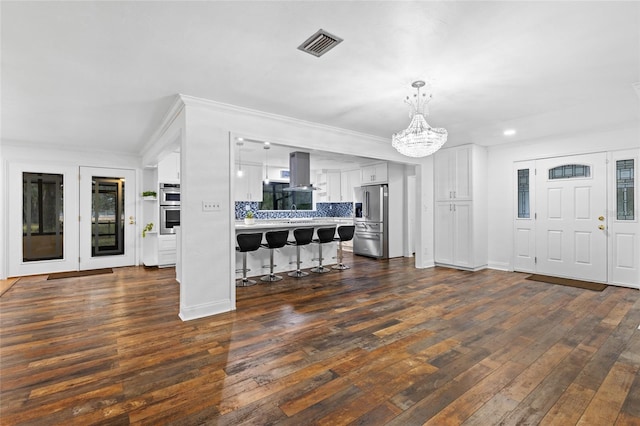 interior space with a breakfast bar, white cabinetry, island exhaust hood, stainless steel appliances, and dark wood-type flooring