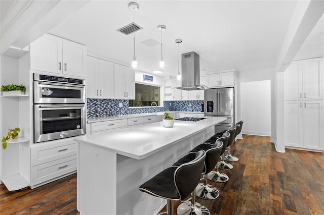 kitchen featuring white cabinetry, island range hood, decorative light fixtures, a center island, and appliances with stainless steel finishes