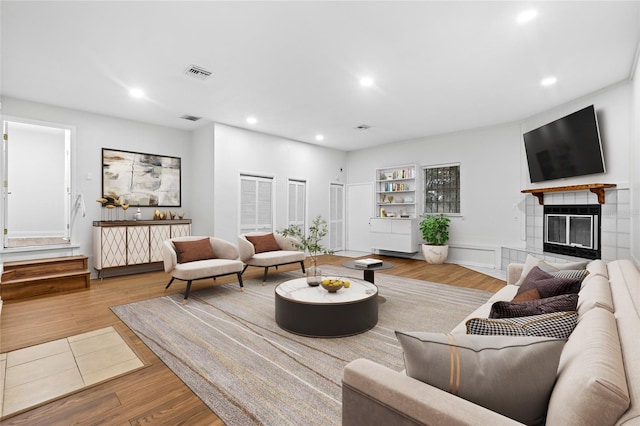 living room with a tiled fireplace and light hardwood / wood-style floors