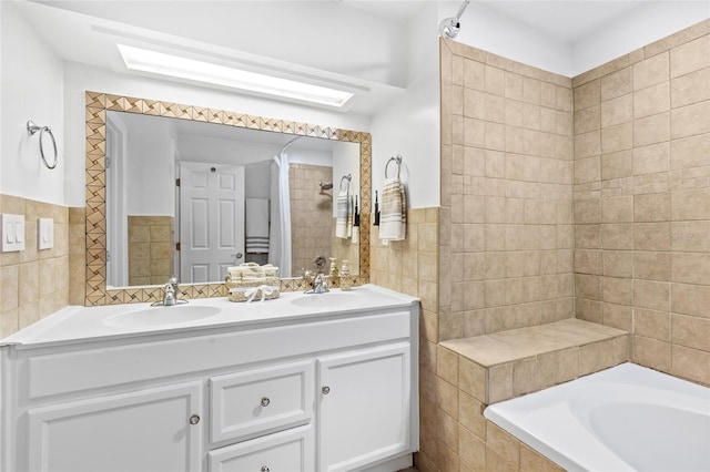 bathroom with vanity, tile walls, a washtub, and a skylight