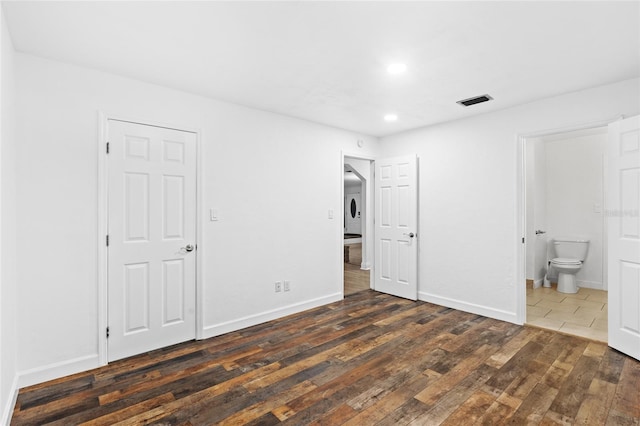 unfurnished bedroom with dark wood-type flooring and ensuite bath