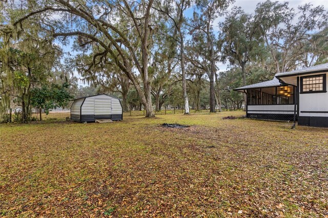 view of yard featuring a sunroom and a storage unit