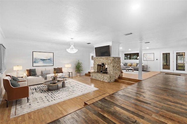 living room with a fireplace, wood-type flooring, decorative columns, and ornamental molding