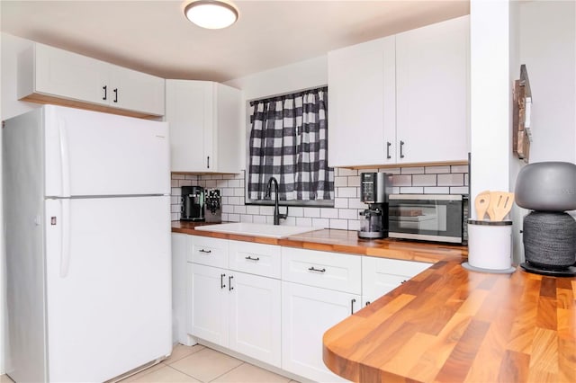 kitchen featuring white refrigerator, white cabinets, sink, and butcher block counters