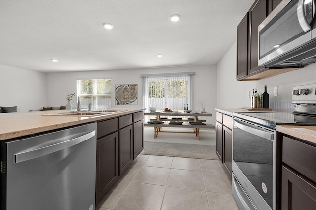 kitchen featuring light tile patterned floors, stainless steel appliances, dark brown cabinets, and sink