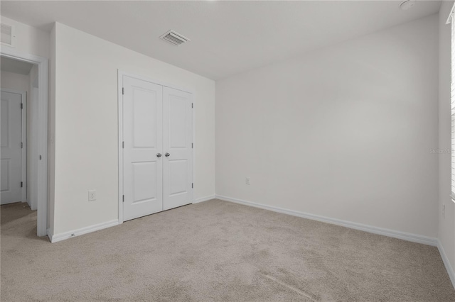 unfurnished bedroom featuring light colored carpet and a closet