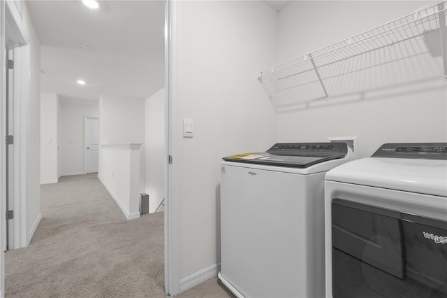 clothes washing area with separate washer and dryer and light colored carpet