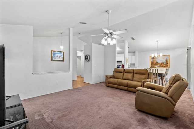 carpeted living room featuring ceiling fan with notable chandelier and vaulted ceiling