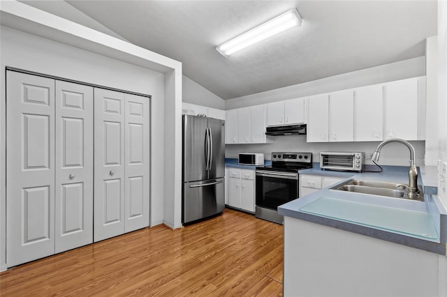 kitchen featuring vaulted ceiling, appliances with stainless steel finishes, light wood-type flooring, white cabinets, and sink