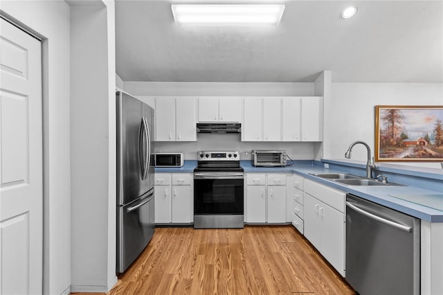 kitchen with white cabinets, stainless steel appliances, light wood-type flooring, and sink