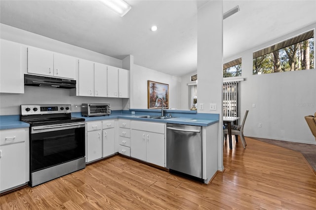 kitchen featuring appliances with stainless steel finishes, light wood-type flooring, white cabinets, lofted ceiling, and sink