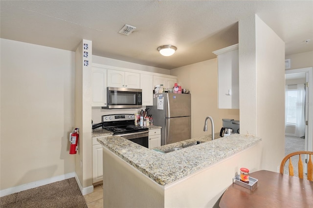 kitchen featuring appliances with stainless steel finishes, white cabinetry, sink, light stone counters, and kitchen peninsula