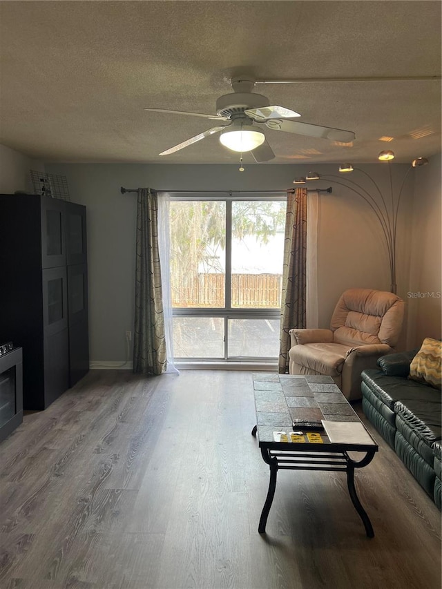 living room with wood-type flooring, ceiling fan, and a textured ceiling