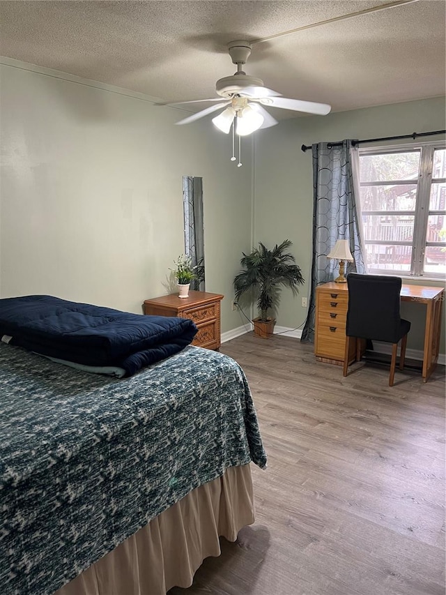 bedroom with ceiling fan, light hardwood / wood-style flooring, and a textured ceiling