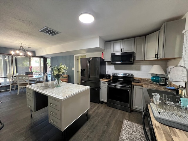 kitchen featuring an inviting chandelier, range with electric stovetop, gray cabinets, black refrigerator with ice dispenser, and a kitchen island