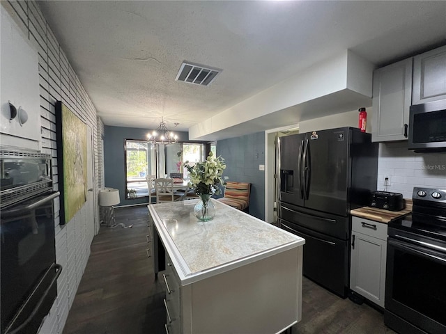 kitchen featuring black appliances, a center island, hanging light fixtures, dark hardwood / wood-style floors, and a chandelier