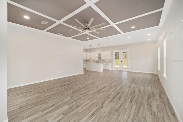 unfurnished living room with coffered ceiling, french doors, ceiling fan, and light wood-type flooring