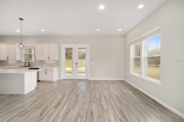 kitchen featuring pendant lighting, sink, light hardwood / wood-style flooring, white cabinets, and french doors