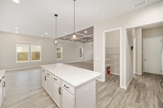 kitchen featuring pendant lighting, a center island, light hardwood / wood-style flooring, and white cabinets