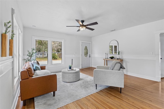 living room with visible vents, ceiling fan, baseboards, and wood finished floors