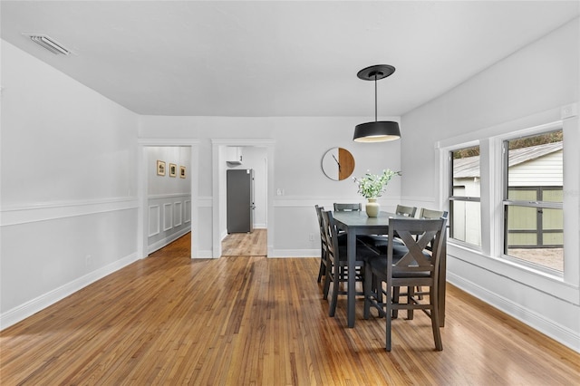 dining area with baseboards, visible vents, and wood finished floors