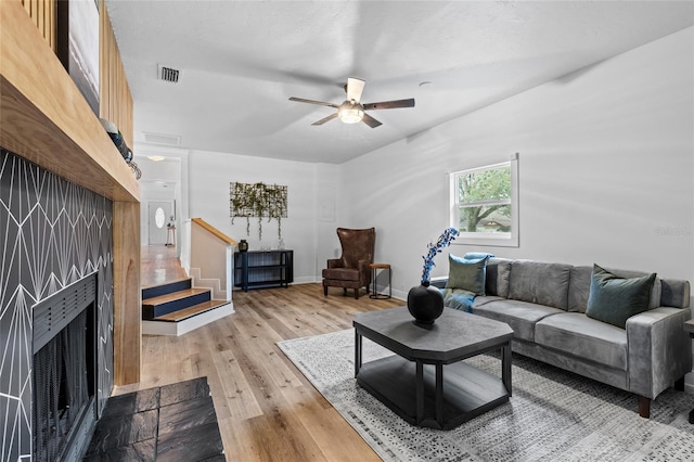 living room with visible vents, stairway, a ceiling fan, light wood-type flooring, and baseboards