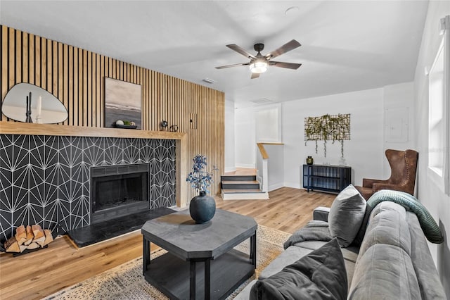 living room featuring a tiled fireplace, ceiling fan, and hardwood / wood-style flooring