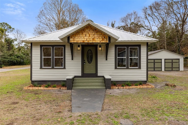 bungalow-style home featuring a garage, metal roof, an outdoor structure, and a front yard