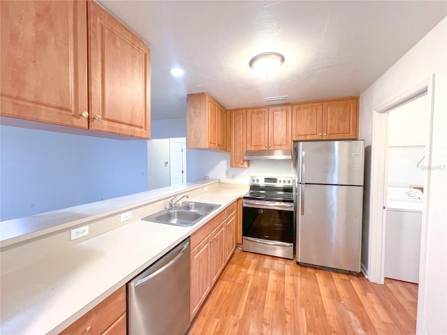 kitchen featuring appliances with stainless steel finishes, light hardwood / wood-style flooring, washer / clothes dryer, and sink