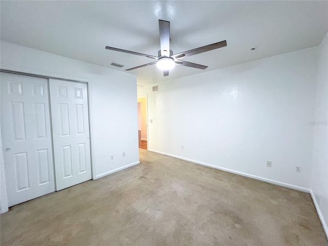 unfurnished bedroom featuring light colored carpet, ceiling fan, and a closet