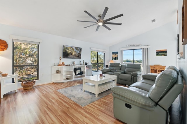 living room with ceiling fan, vaulted ceiling, and light wood-type flooring